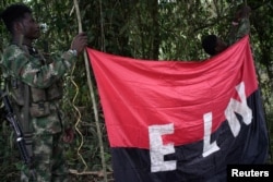 ARCHIVO - Rebeldes del Ejército de Liberación Nacional sostienen una bandera en la selva noroeste de Colombia el 30 de agosto de 2017.